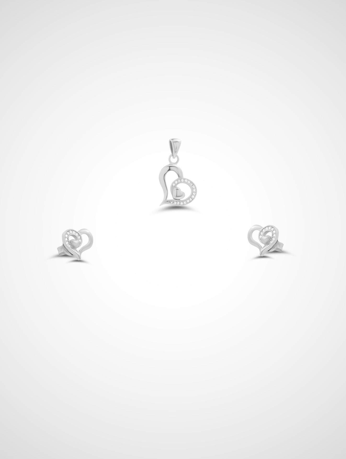 Silver heart-shaped pendant and earrings on a white background