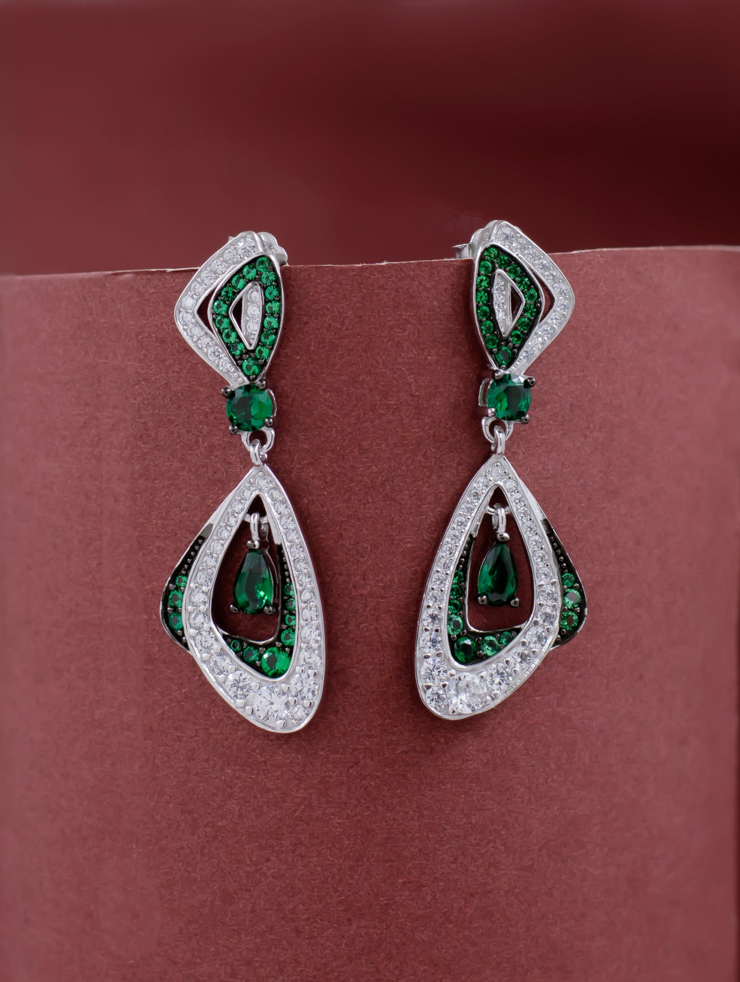 Elegant silver earrings featuring emerald center and zircon border.
