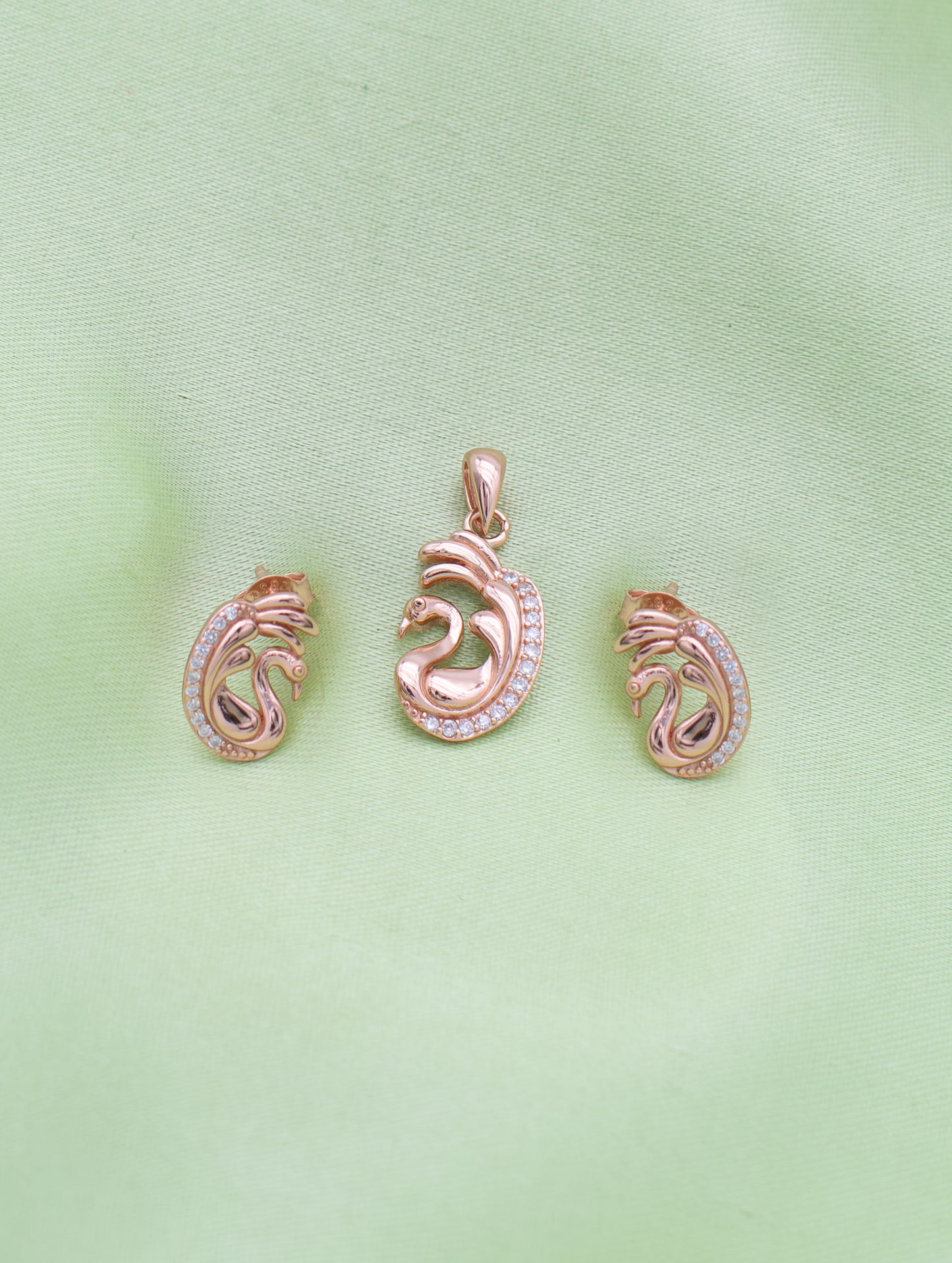 Close-up of rose gold swan pendant with sparkling zircon detailing and curved wings.