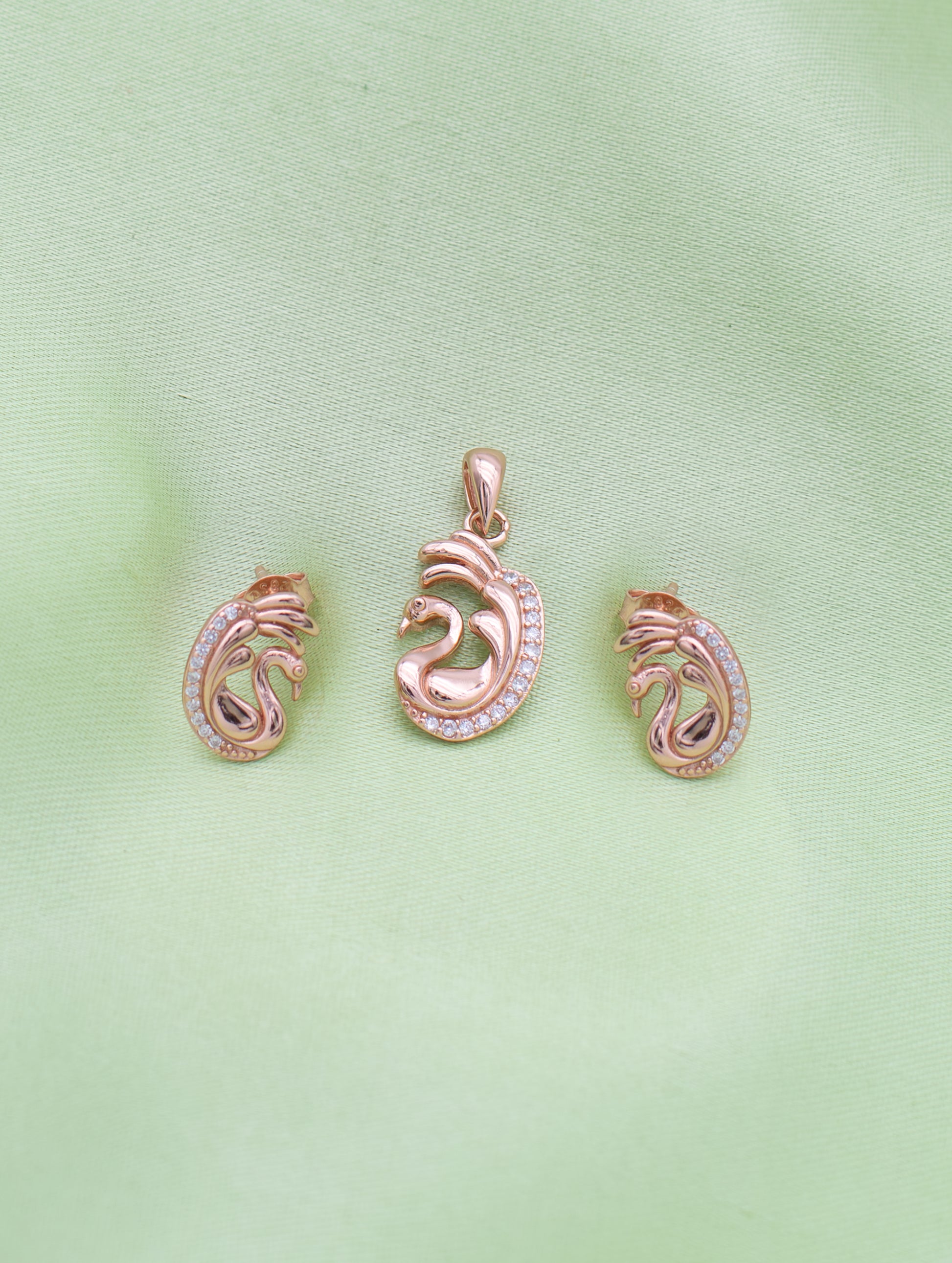 Close-up of rose gold swan pendant with sparkling zircon detailing and curved wings.