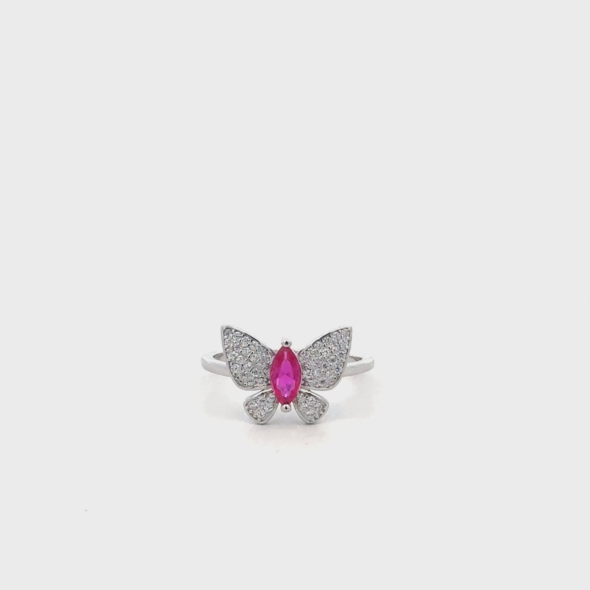 Close-up of sterling silver ring featuring butterfly design with pink accent stone.
