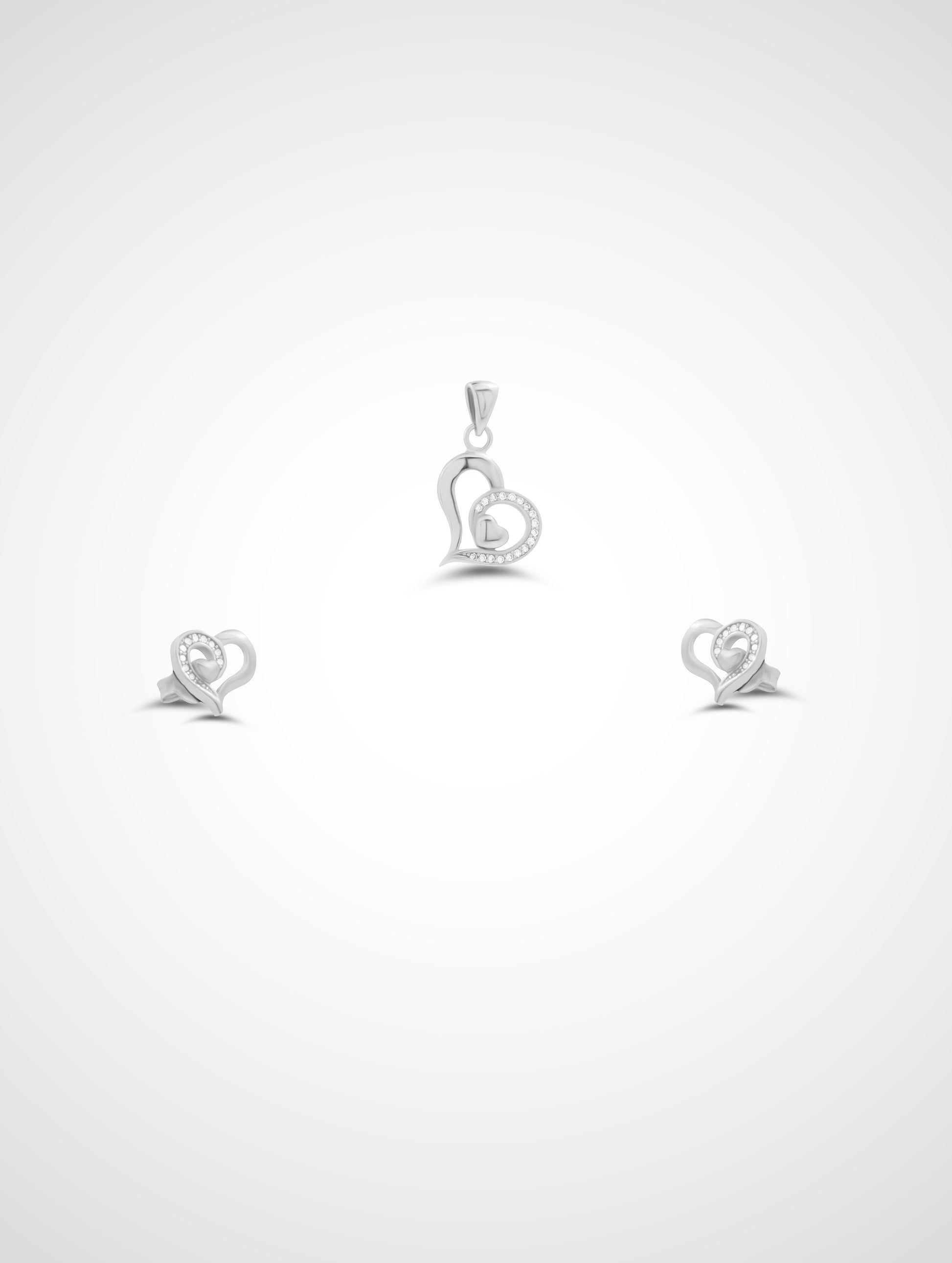Silver heart-shaped pendant and earrings on a white background